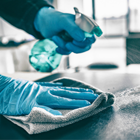 Image of a person disinfecting a surface. 