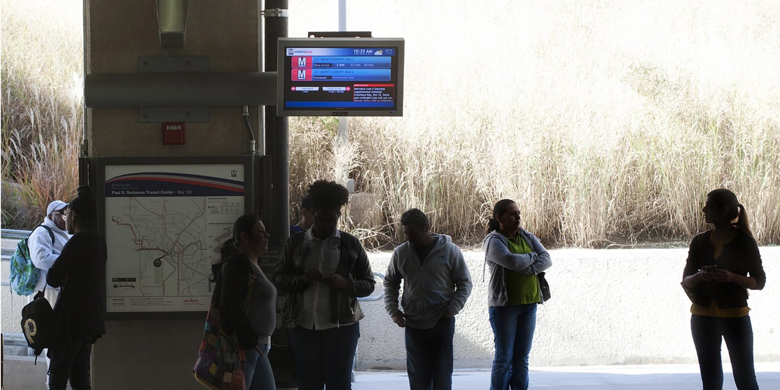Picture of people at a train station with Redmon transit display
